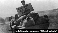 Представник радянської влади везе конфісковане у селян зерно на пункт здачі зерна. Репродукція. Місце і дата зйомки: УССР, 1933 рік 