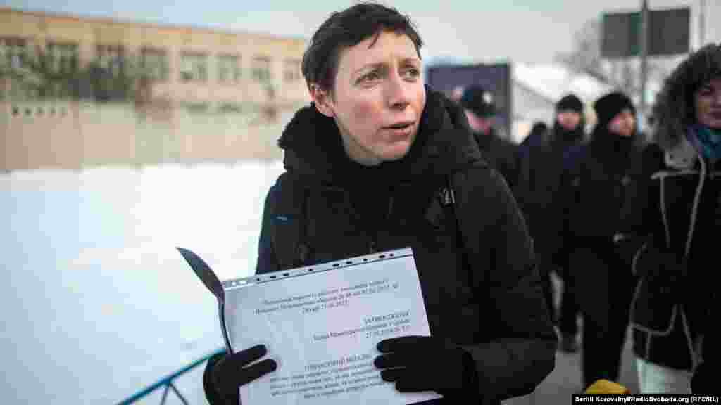 Учасниця ходи тримає в руках папери, що засвідчують на законодавчому рівні статеву дискримінацію жінок в армії. Зокрема, кількість посад, які може обіймати жінка в армії, лишається мізерно малою: снайперки та гранатометниці офіційно зараховані &laquo;кухарками&raquo; чи &laquo;начальницями лазні&raquo;