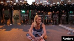 Кармалган демонстранттардын биринин апасы экенин айткан аял Белграддагы полиция имаратынын алдында турат, 17-март, 2019-жыл. 