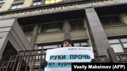 Москвада Думанын имаратынын алдында "Журналист аялдардан колуңарды тарткыла!" деген ураанды көтөрүп турган аял.  21-март, 2018-жыл. 