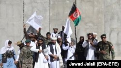 پرچم ملی افغانستان به همراه پرچم طالبان در کنار جنگجویان طالبان و سربازان ارتش در آتش‌بس سه روزه در روز دوم عید فطر ۱۶ جون ۲۰۱۸ 