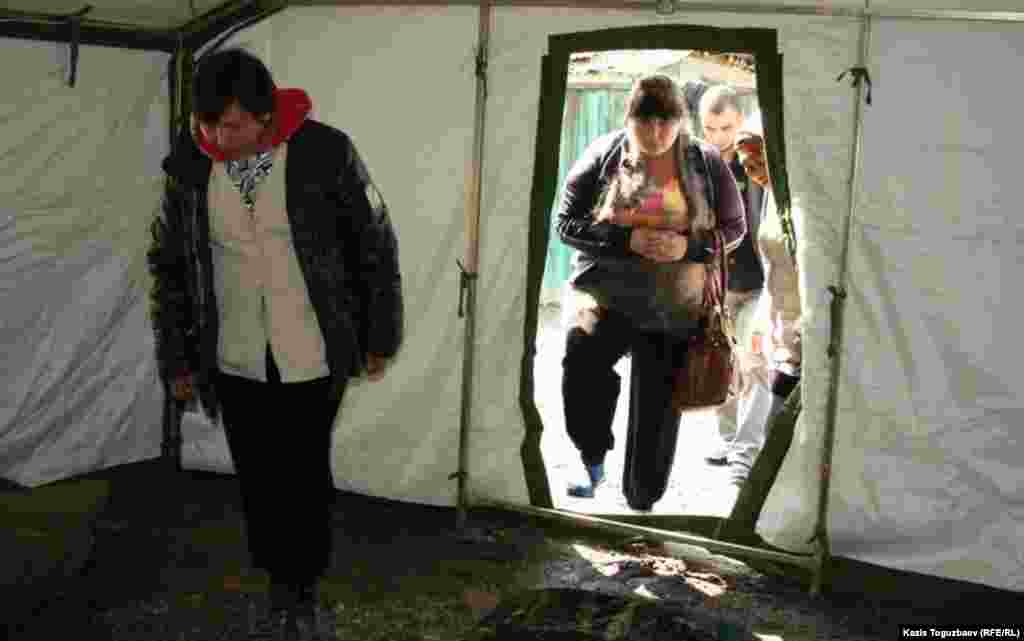 Люди входят в палатку, установленную для жильцов сгоревшего дома в Турксибском районе Алматы.