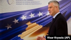 President Hashim Thaci stands in front of a banner marking the 10th anniversary of Kosovo's independence during an interview with the Associated Press in Pristina on February 14.