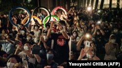 Люди спостерігають за феєрверками під час церемонії відкриття Олімпійських ігор-2020 біля Олімпійського стадіону в Токіо 23 липня 2021 року