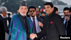 Afghan President Hamid Karzai (left) shakes hands with Indian Minister of State for Home Affairs R.P.N Singh upon his arrival at the airport in New Delhi on December 12.
