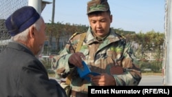 Кыргыз чек арачысы "Достук" өткөрмө бекетинен өтүп бараткан жарандын документин текшерүүдө, 26-октябрь.