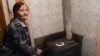 80-летняя жительница многоэтажного дома Галина Осипова сидит рядом с самодельной печкой-буржуйкой. Поселок Шахан, Карагандинская область, 10 января 2017 года. 