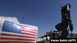 تصویر آرشیف: یکی از افراد طالبان از کنار بیرق ایالات متحده در میدان هوایی بین المللی کابل عبور می کند
